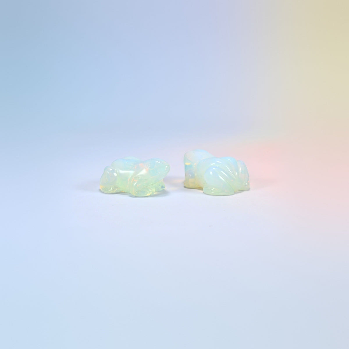Two opalite frog carvings, milky man-made glass with a soft glow