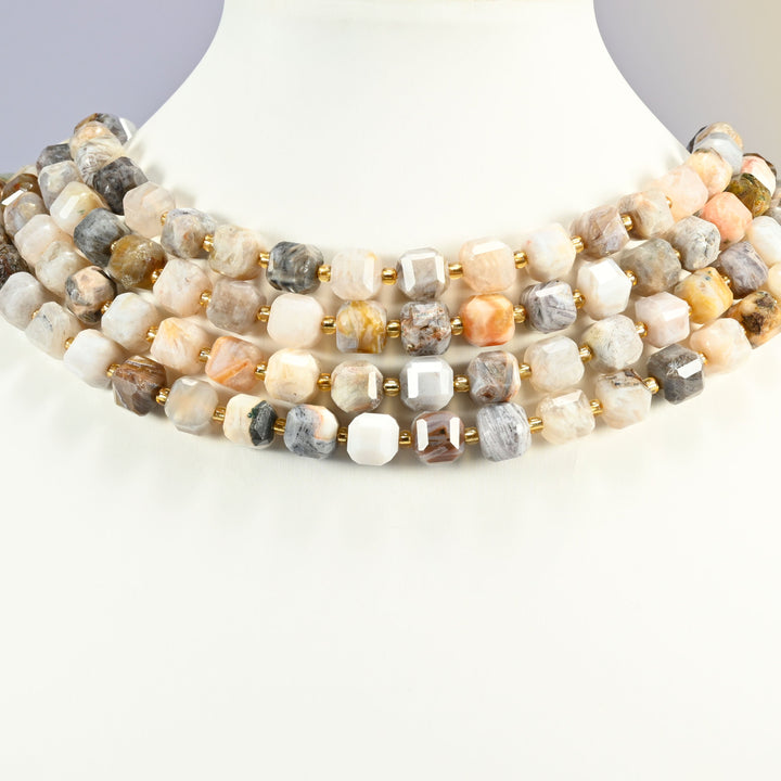 Bamboo agate faceted cube strands arranged as a layered collar on a white display bust, cream, gray and tan beads across the neck