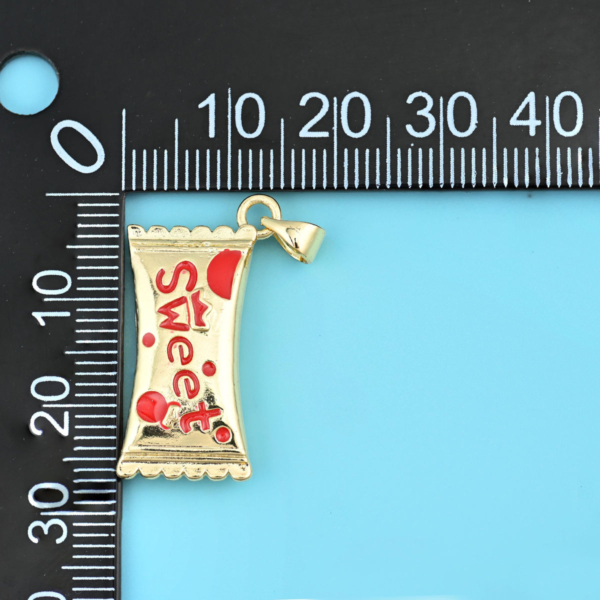 27mm enamel sweet candy charm on a black millimetre ruler, running to about 27mm.