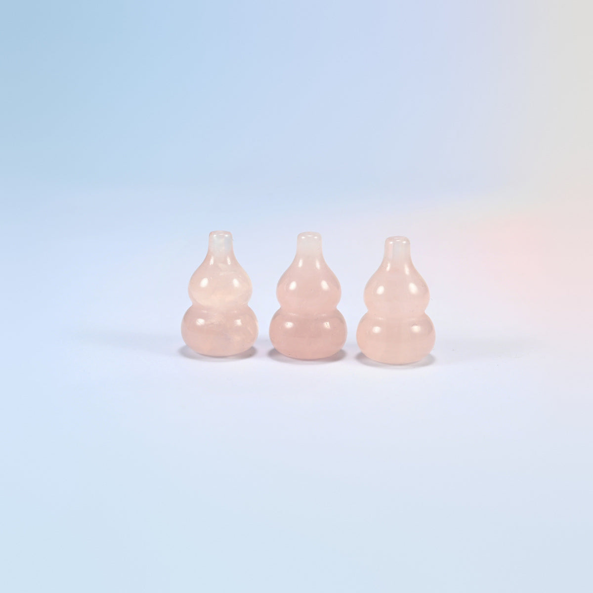 Three natural rose quartz gourd crystal carvings, soft glowing pink