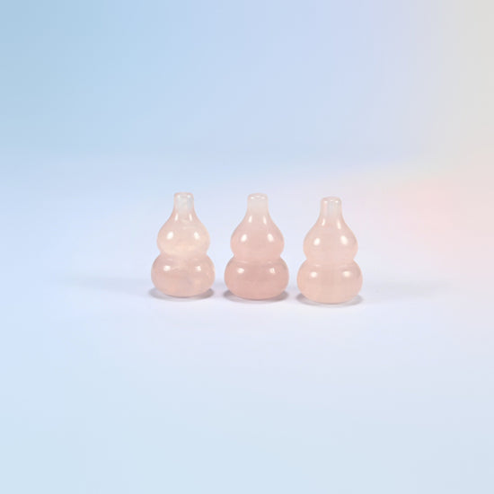 Three natural rose quartz gourd crystal carvings, soft glowing pink