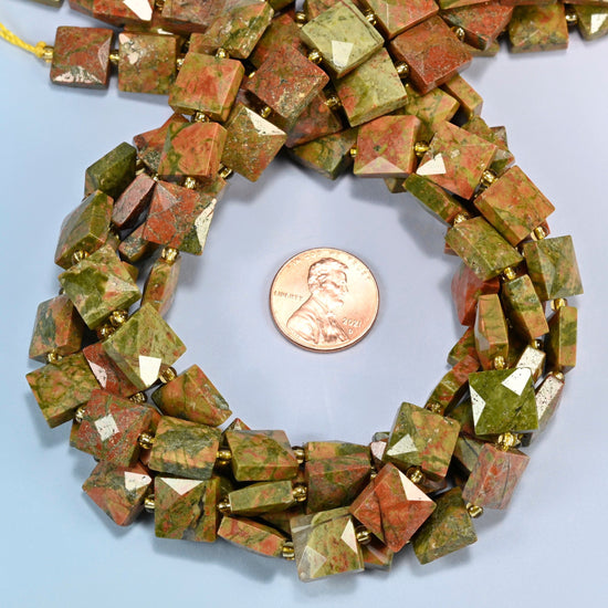 Natural unakite faceted flat square beads 10x10mm coiled in a loop around a US penny for scale, close-up of the faceted flat square shape