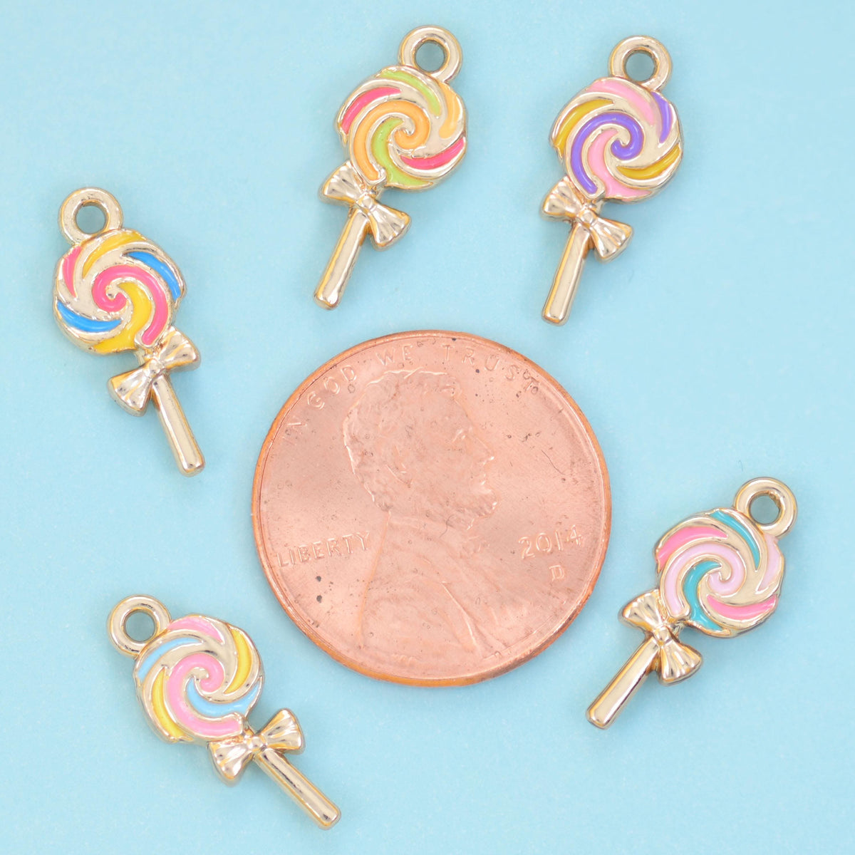 Enamel lollipop charms arranged around a US penny, each charm smaller than the coin.