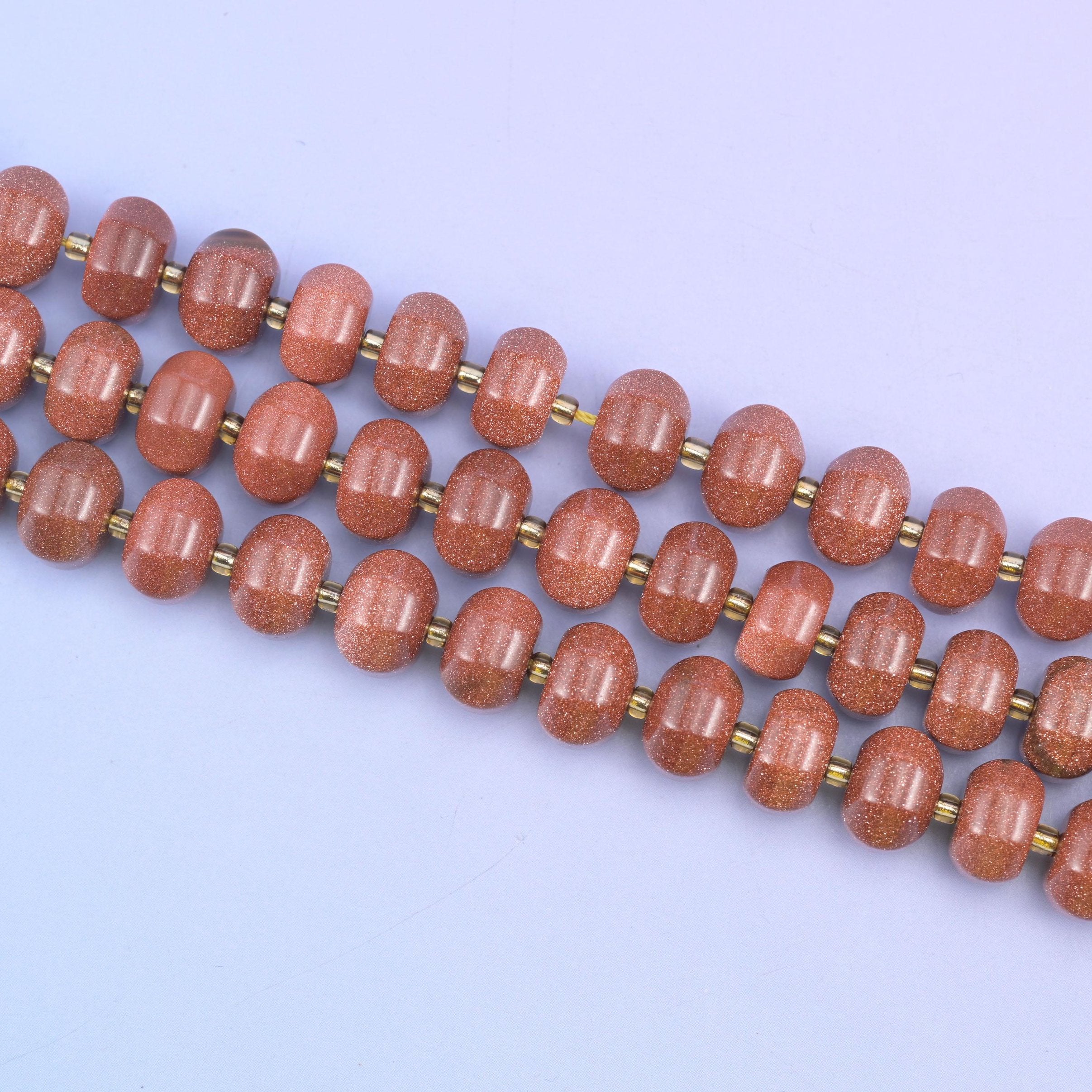 Gold sandstone beads in warm brown-red flecked with sparkling copper glitter