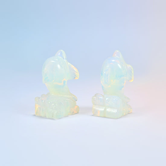 Two opalite dolphin figurines from behind showing the wave detail