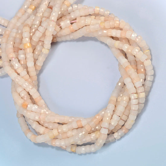 Pink aventurine faceted heishi disc beads coiled into overlapping loops, whole strands of soft peach pink stone