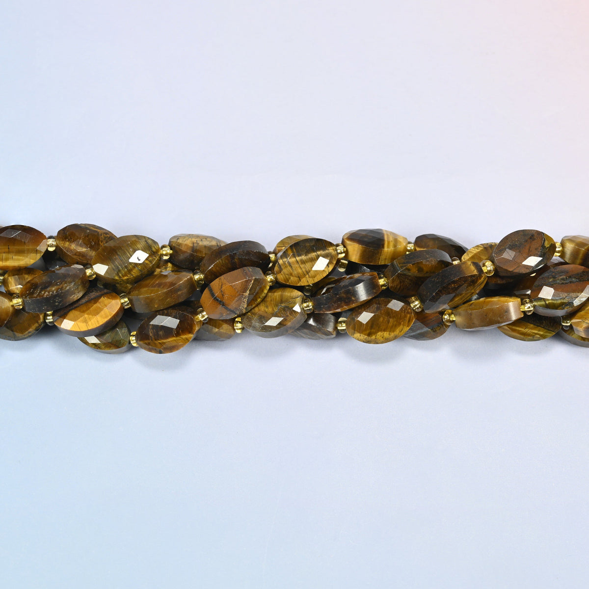 Strands of tiger eye faceted flat oval beads twisted together in a horizontal row