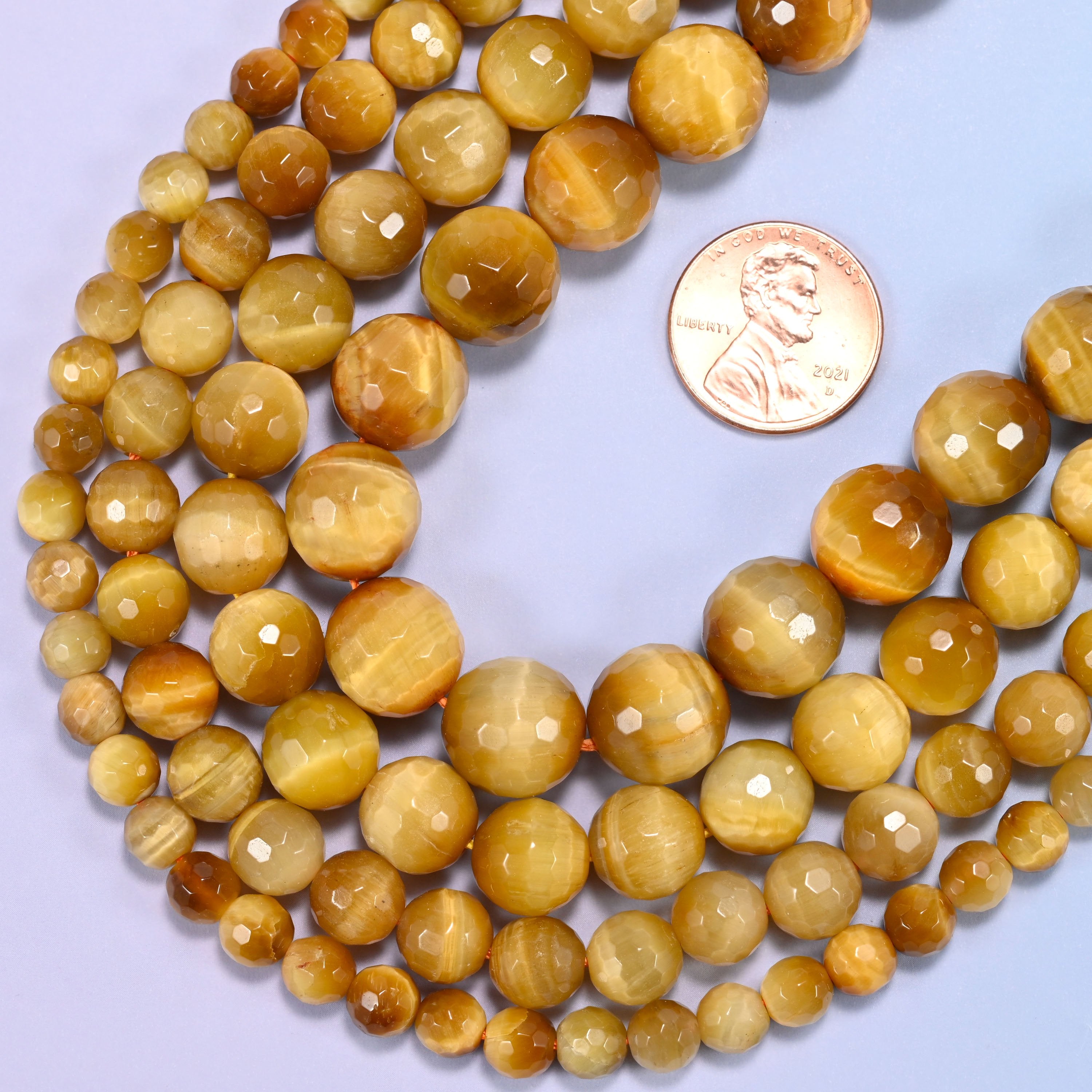 Golden brown gold tiger eye round beads in 6mm, 8mm, 10mm, and 12mm grouped together to compare sizes.