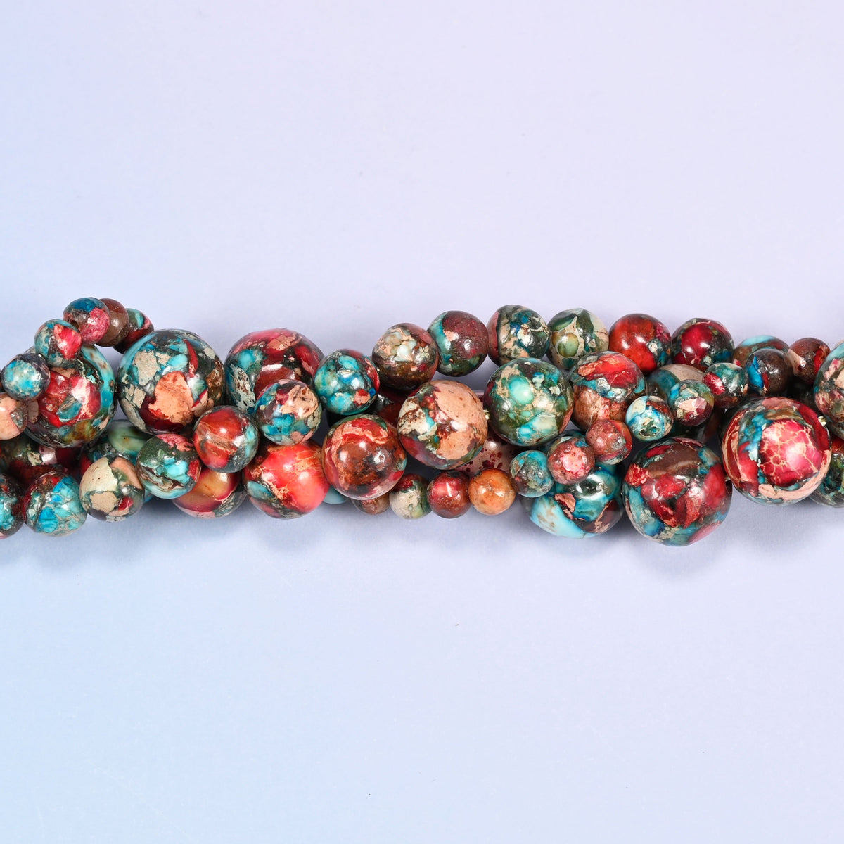 A short run of red sea sediment jasper round beads laid in a gentle wave straight across the frame.