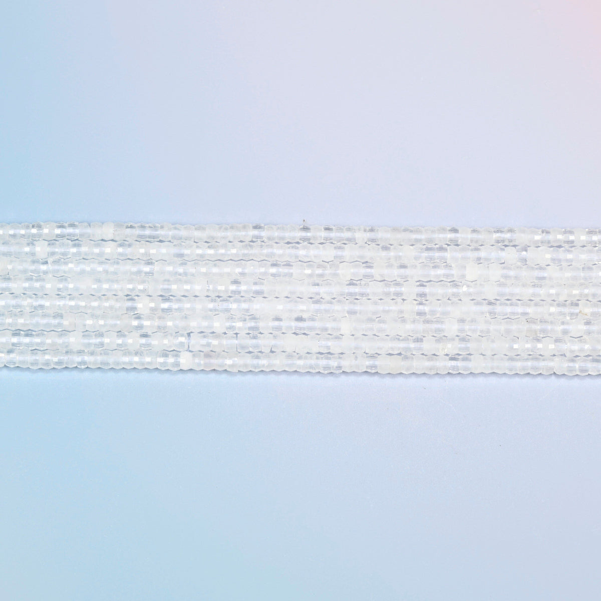 Several strands of clear quartz faceted heishi disc beads laid in straight rows