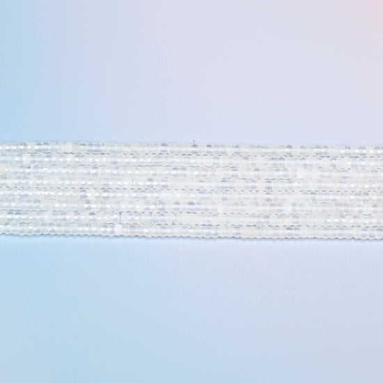 Several strands of clear quartz faceted heishi disc beads laid in straight rows
