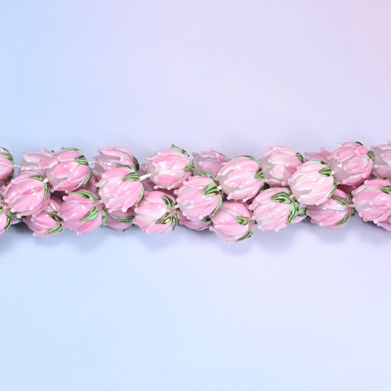 Pink tulip bud-shaped lampwork glass beads, hand-formed with sculpted petal detailing that gives a realistic flower bud look, accented with a green leaf detail at the base.