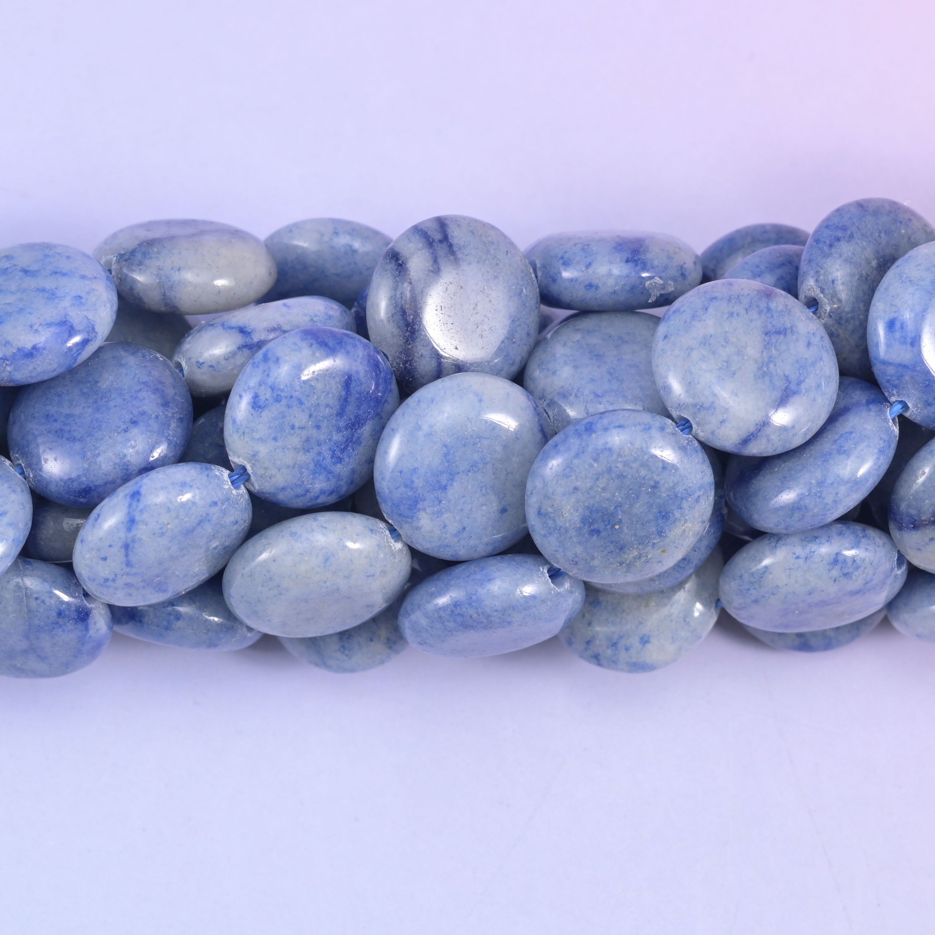 Macro close-up of blue aventurine coins with a satin-polished surface and mottled blue and grey-white banding