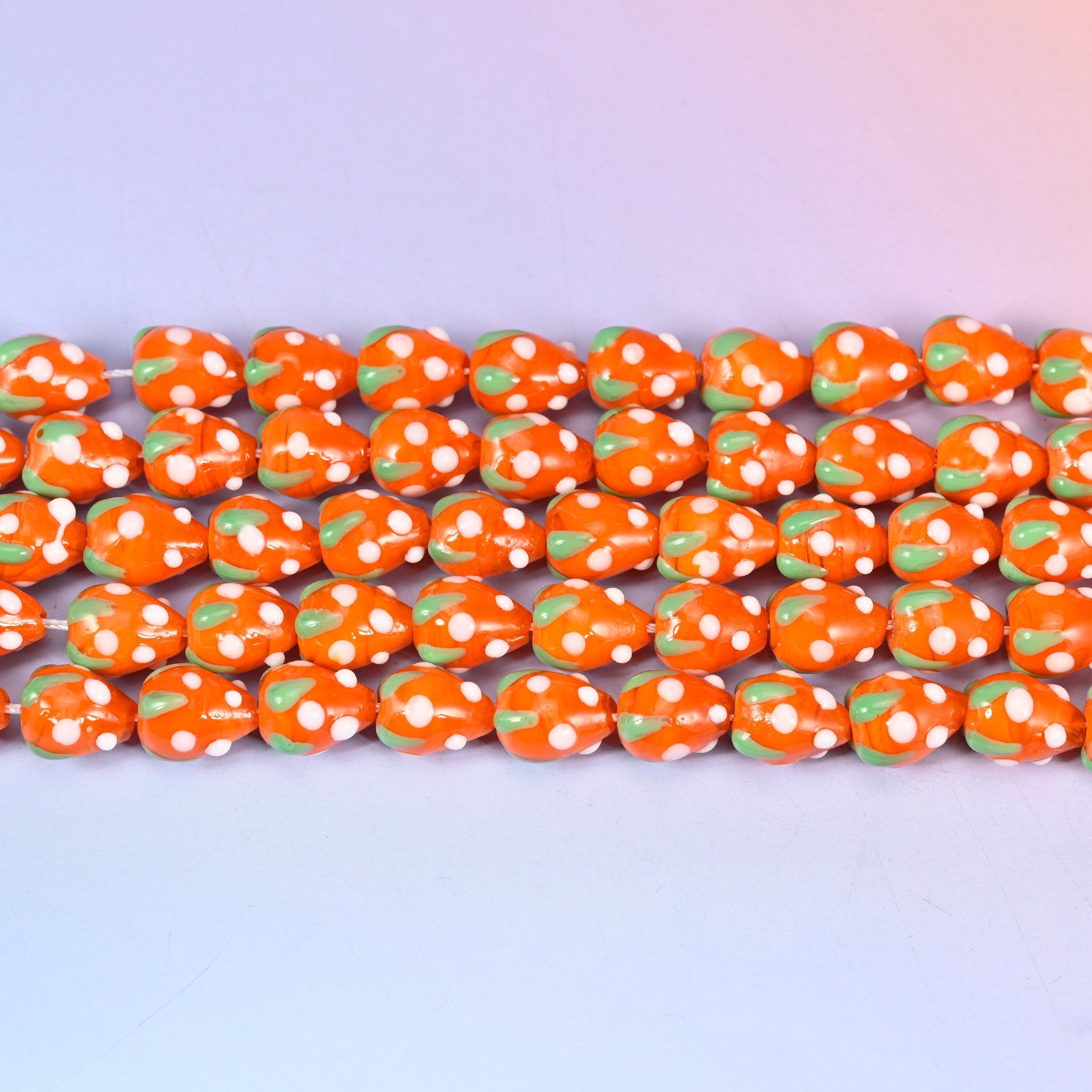Orange White Dots Strawberry Glass Beads in bright glossy orange with a green leaf cap