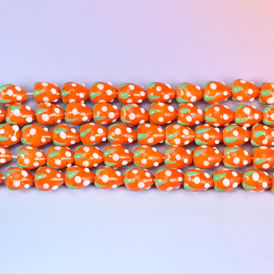 Orange White Dots Strawberry Glass Beads in bright glossy orange with a green leaf cap