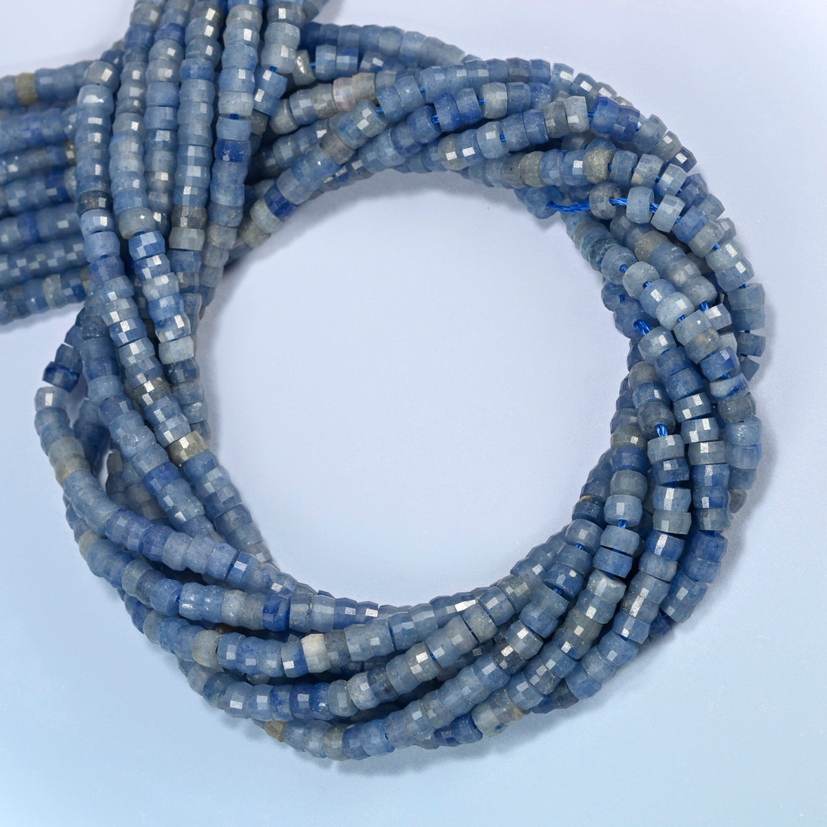 Blue aventurine faceted heishi disc beads coiled into overlapping loops, whole strands of soft light blue stone