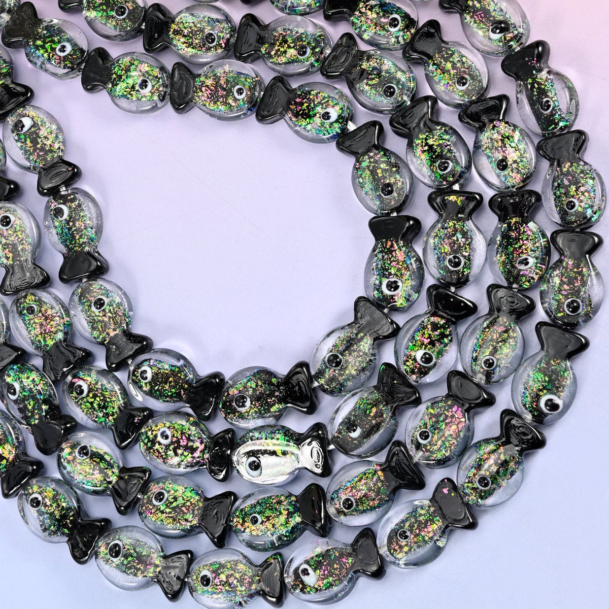 Iridescent Black Green Fish Glass Beads — clear lampwork fish with a dense core of green and gold glitter trapped inside, finished with solid black tails, fins and dot eyes.