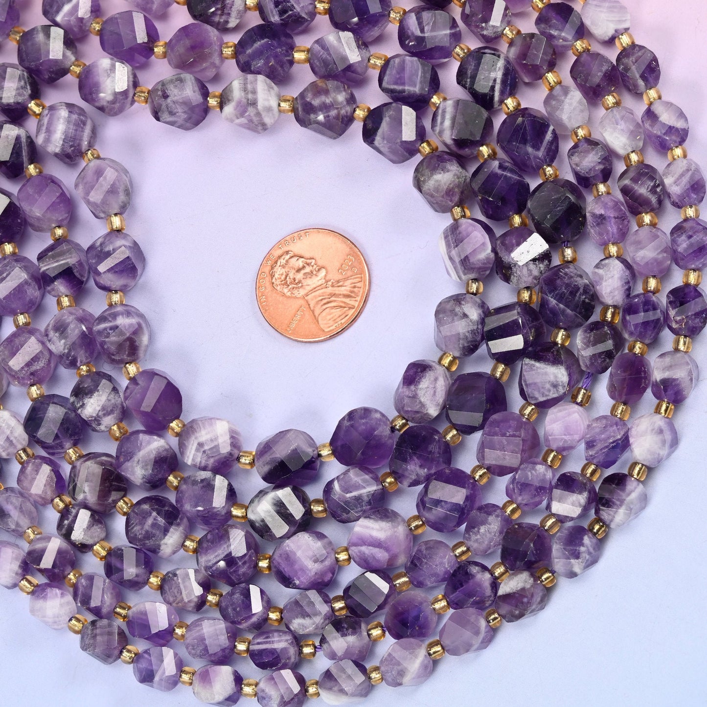 Deep grape purple striped with chalky white in the V-shaped banding that gives chevron amethyst its name, cut into a faceted spiral twist so each bead turns slightly against the next.