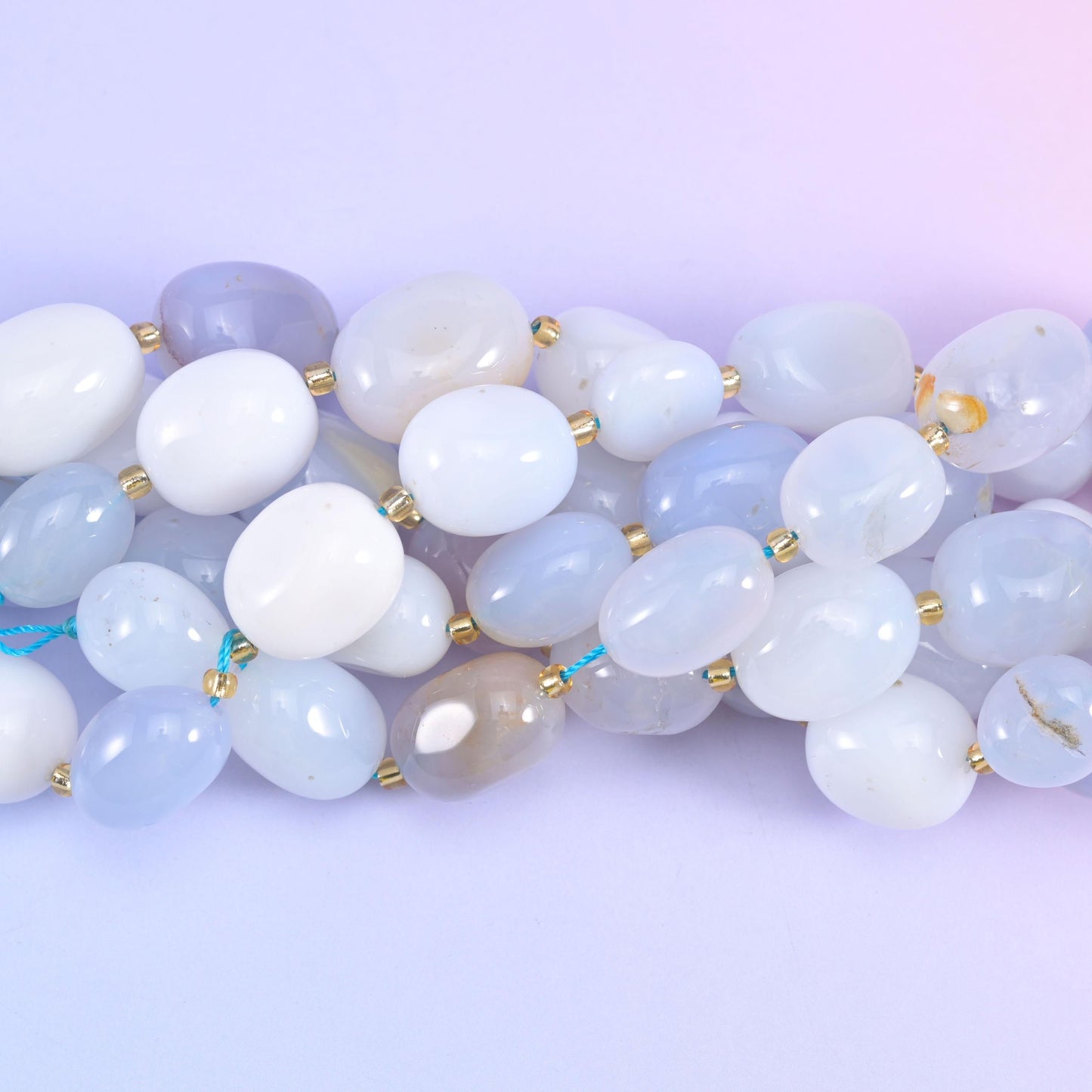 Close view of tumbled chalcedony nuggets, some near-opaque white and others softly translucent
