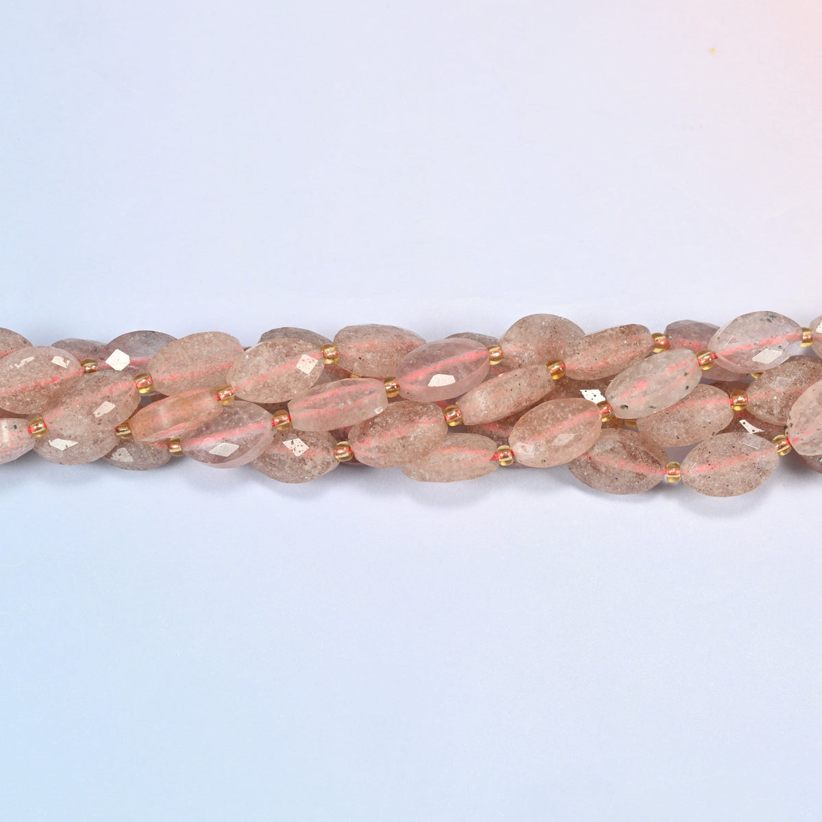 Strands of strawberry quartz faceted flat oval beads twisted together in a horizontal row