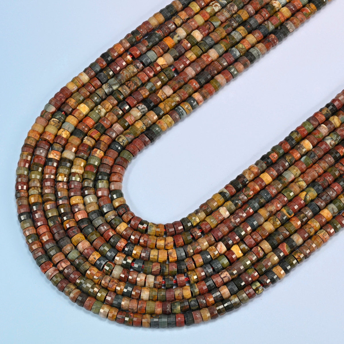 Red howlite faceted heishi disc beads in several strands curved into a wide U, brick red, olive green and tan stone