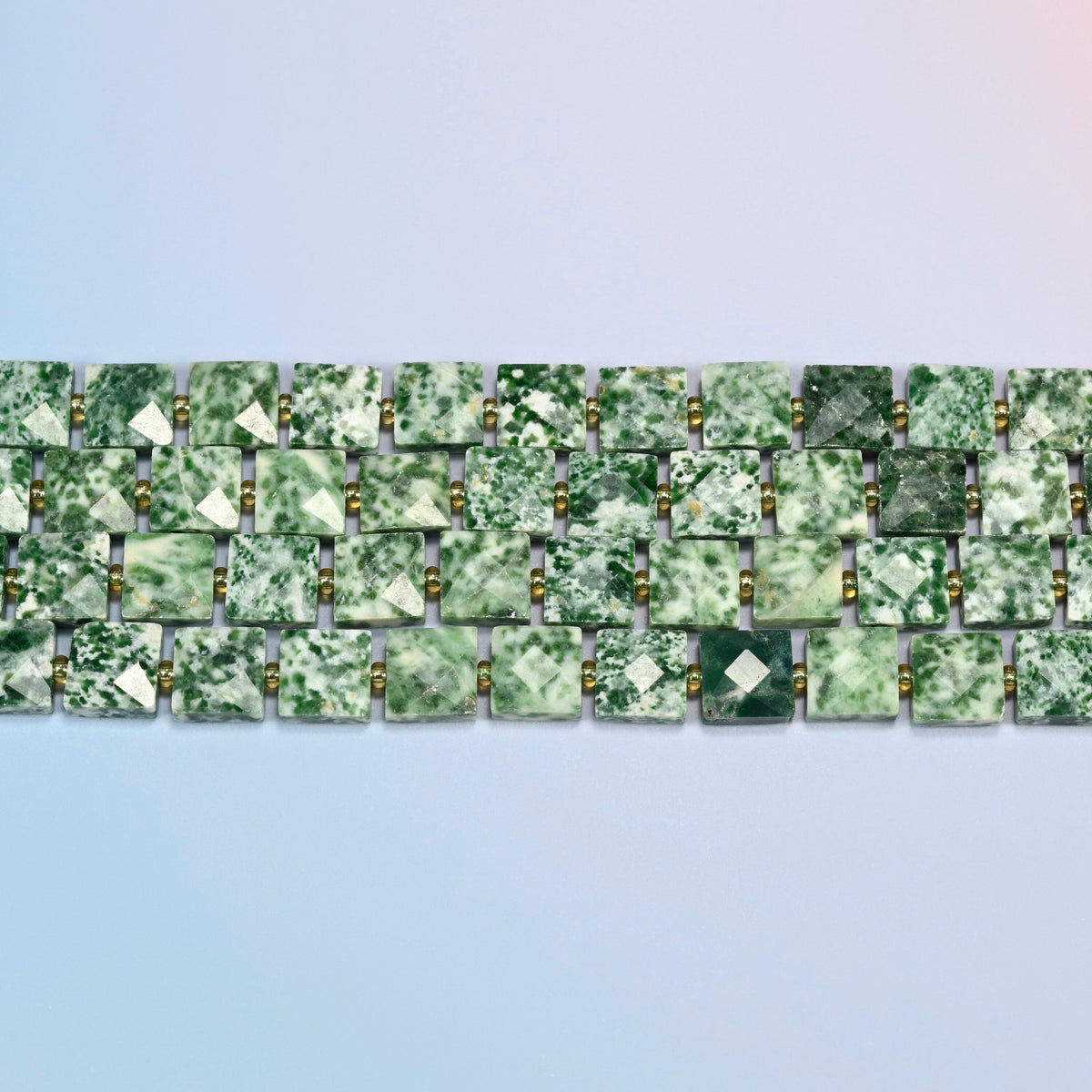 Several strands of tree agate faceted flat square beads laid in straight rows