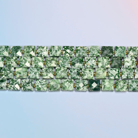 Several strands of tree agate faceted flat square beads laid in straight rows