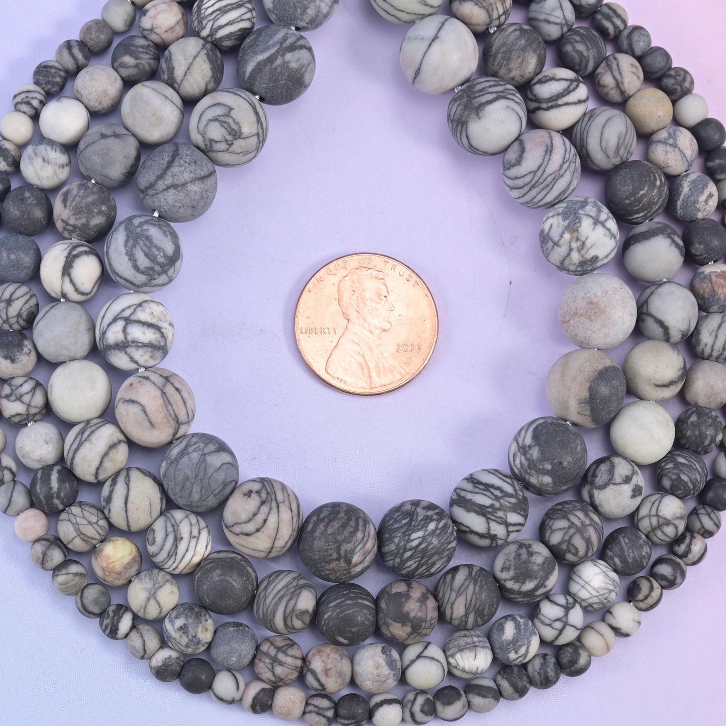 Matte, unpolished rounds in bone cream and warm dove grey, every bead netted with fine charcoal web veining that wanders across the surface like ink on paper
