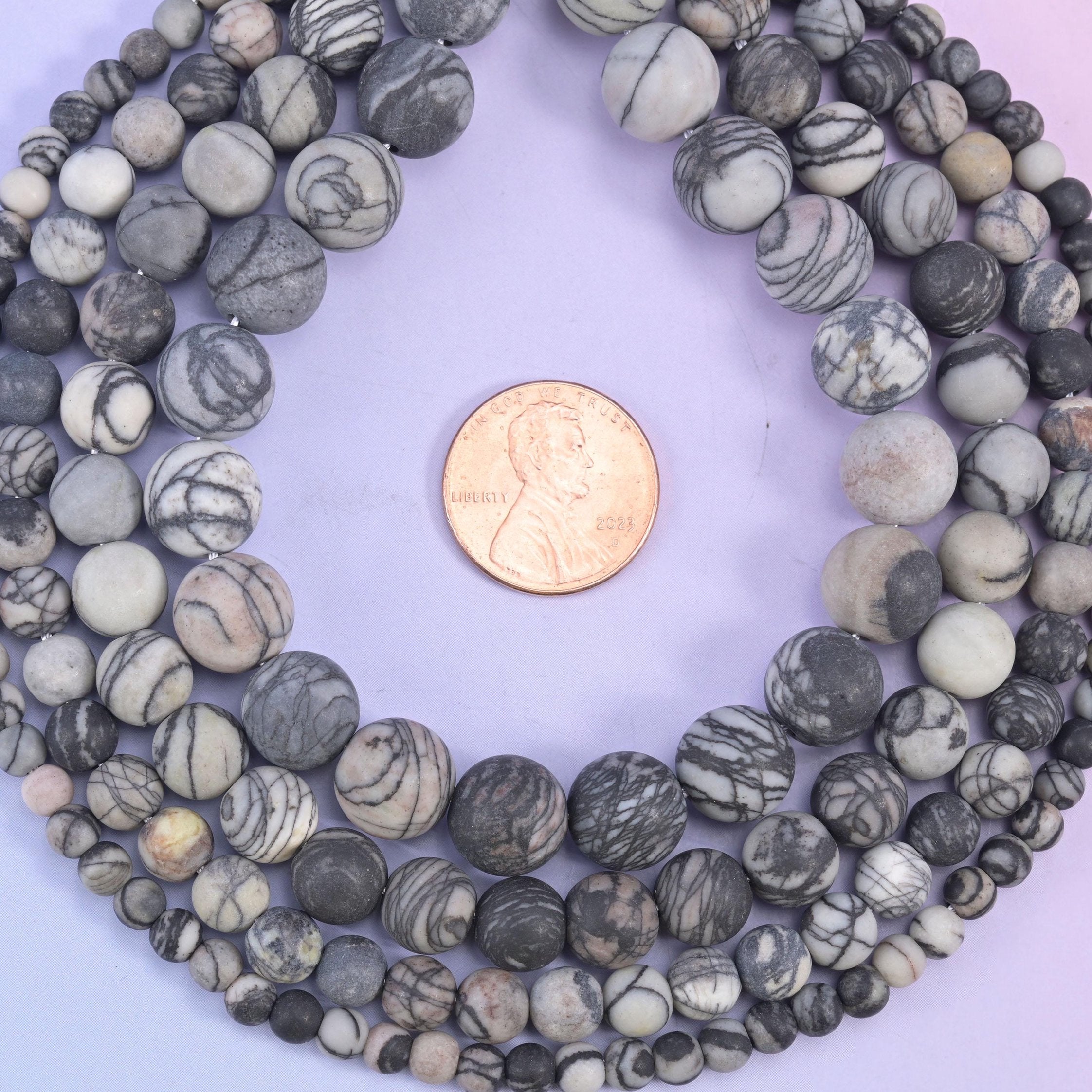 Matte, unpolished rounds in bone cream and warm dove grey, every bead netted with fine charcoal web veining that wanders across the surface like ink on paper