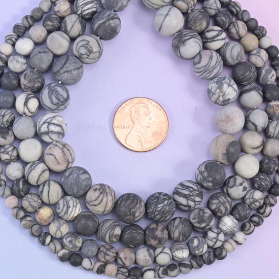 Matte, unpolished rounds in bone cream and warm dove grey, every bead netted with fine charcoal web veining that wanders across the surface like ink on paper