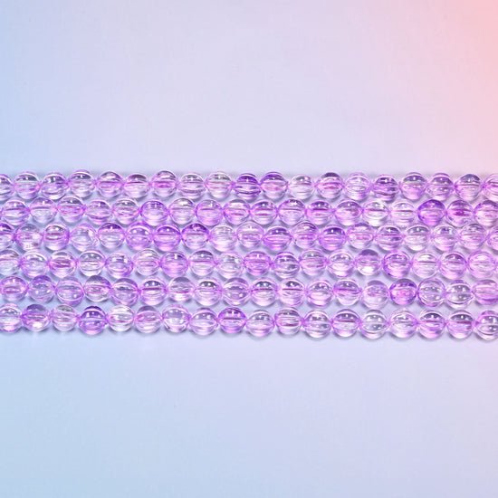 Close-up of 8mm clear purple pumpkin glass beads in four horizontal rows, showing the carved melon ribs.
