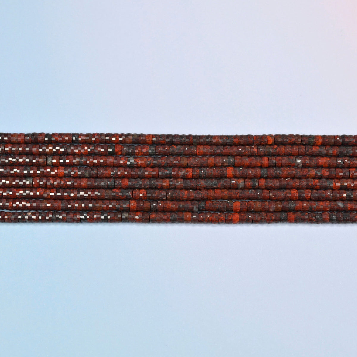 Several strands of Zhanguo red agate faceted heishi disc beads laid in straight rows