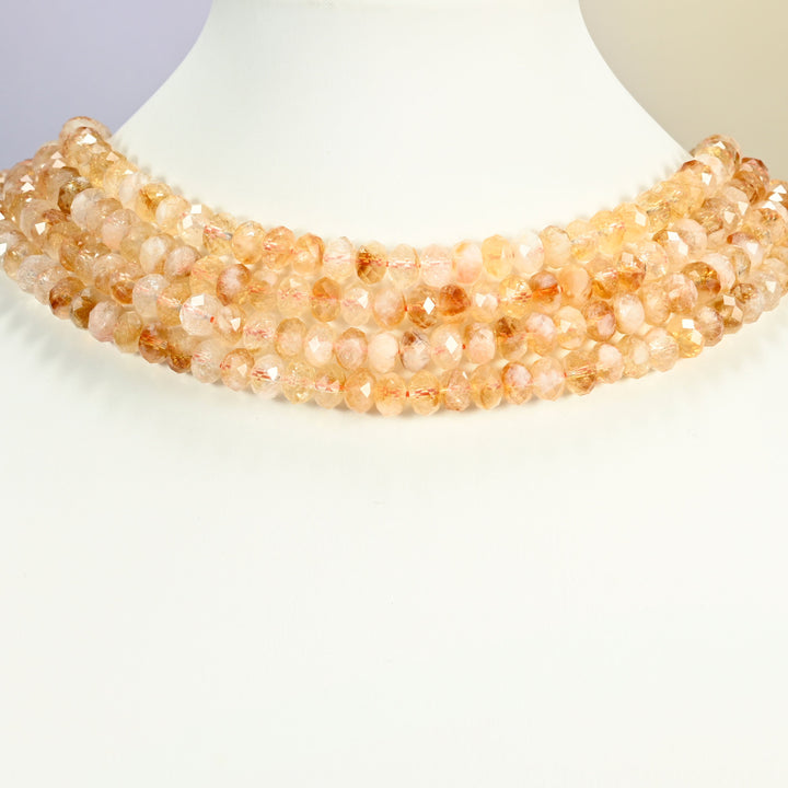 Citrine faceted rondelle strands arranged as a layered collar on a white display bust, warm golden beads across the neck