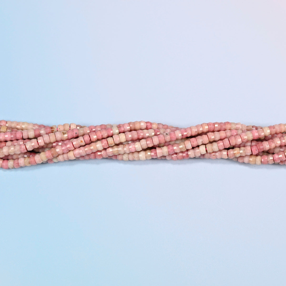 Strands of pink rhodonite faceted heishi disc beads twisted together in a horizontal row