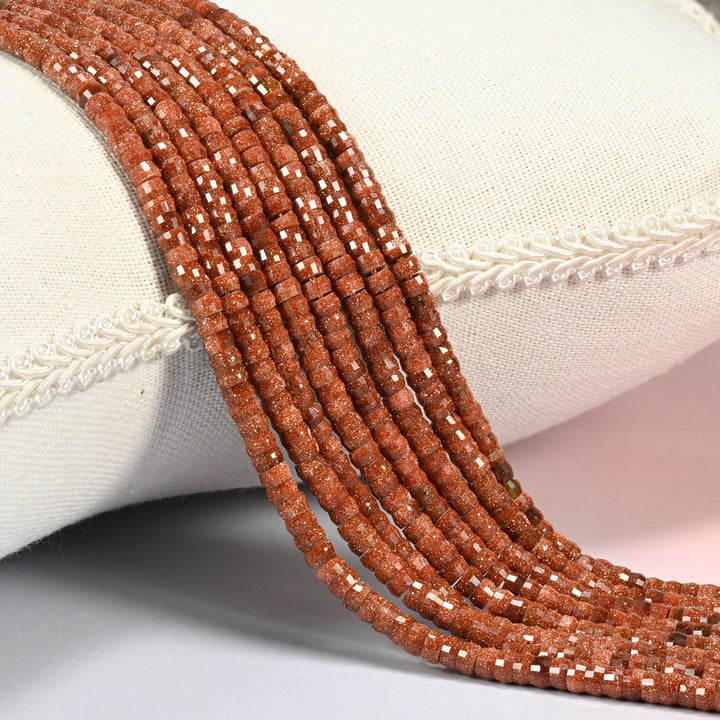 Gold sandstone faceted heishi disc beads 2x4mm, several strands draped over a white cushion