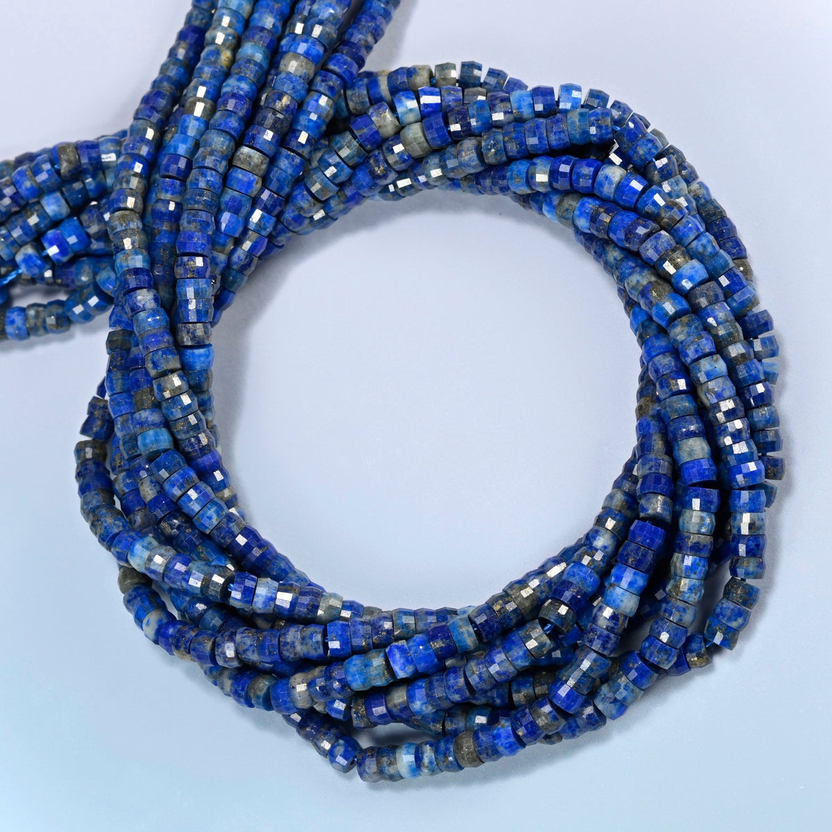 Lapis faceted heishi disc beads coiled into overlapping loops, whole strands of bright blue stone