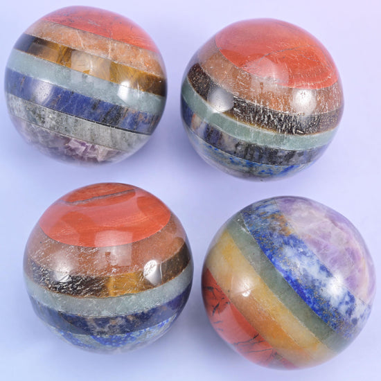 Four large polished spheres with wide orange, blue and grey stripes wrapping right around the curve