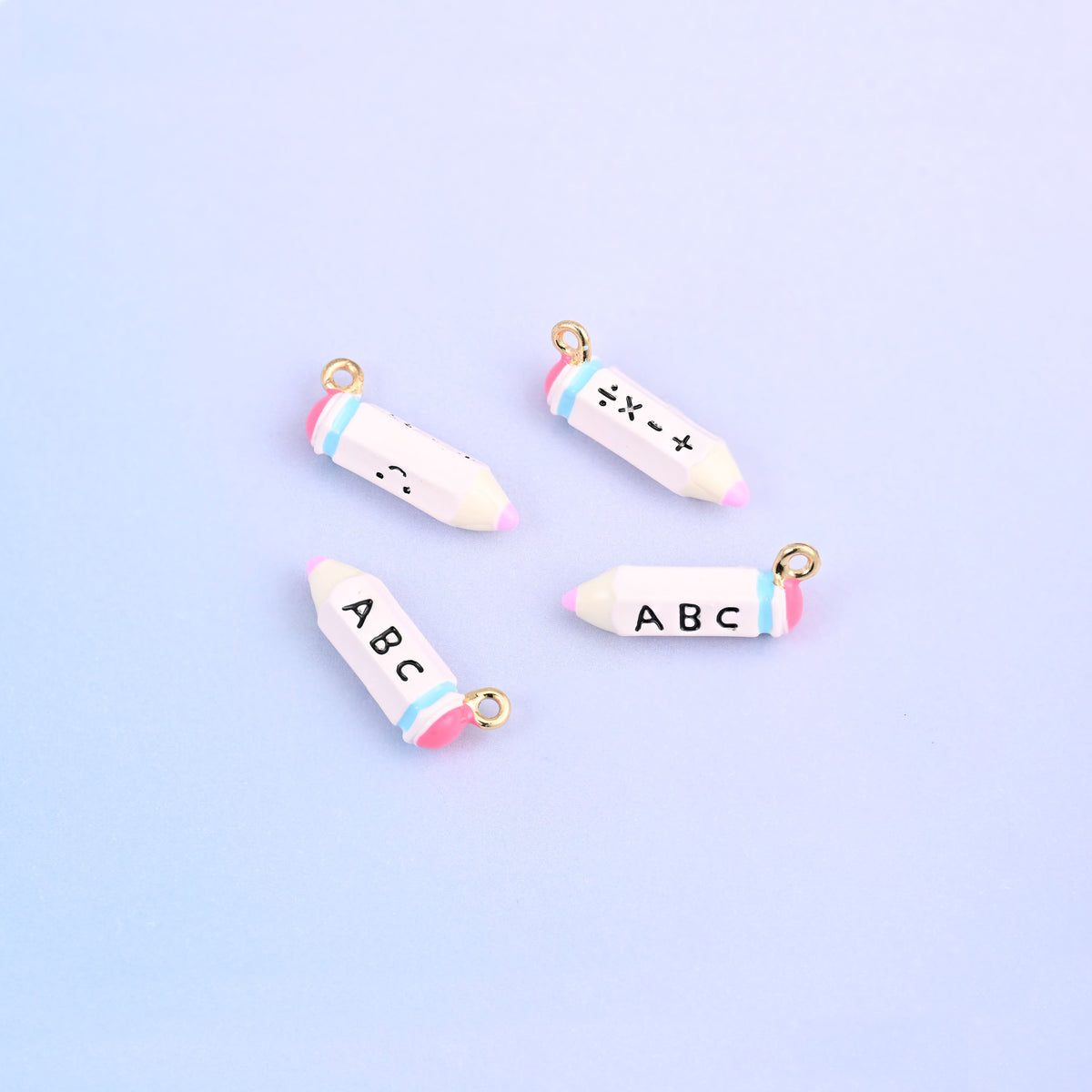 Four white pencil charms with pink bands, lettered ABC on one face and plus minus times divide on the other.