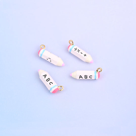 Four white pencil charms with pink bands, lettered ABC on one face and plus minus times divide on the other.