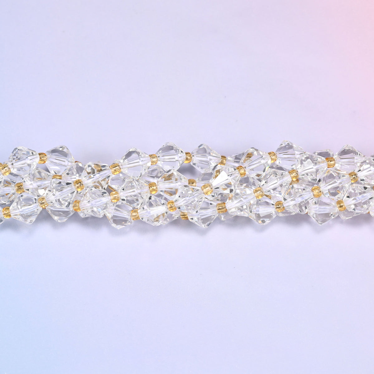 Macro close-up of 8mm Clear Quartz faceted bicone beads on a strand, showing the clear crystal facets in detail.