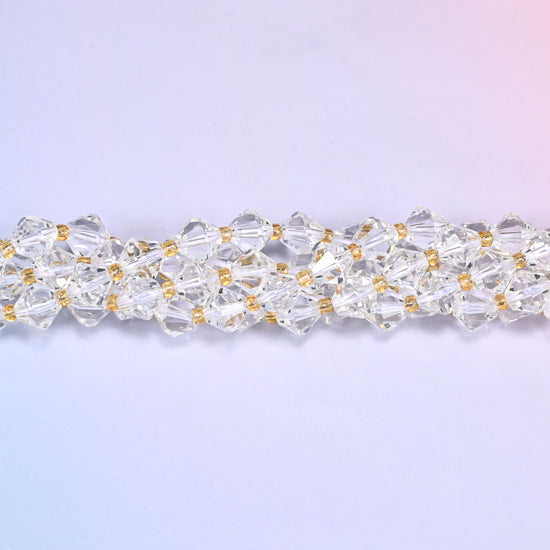 Macro close-up of 8mm Clear Quartz faceted bicone beads on a strand, showing the clear crystal facets in detail.