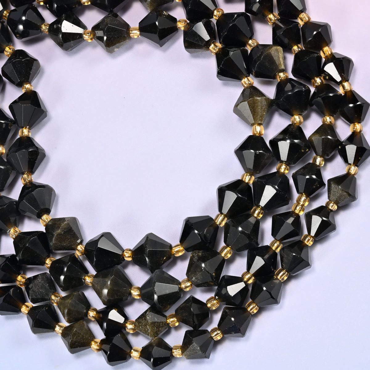 Gold obsidian bicone beads formed into a wide open ring, the sheen shifting from bead to bead as the strand turns.