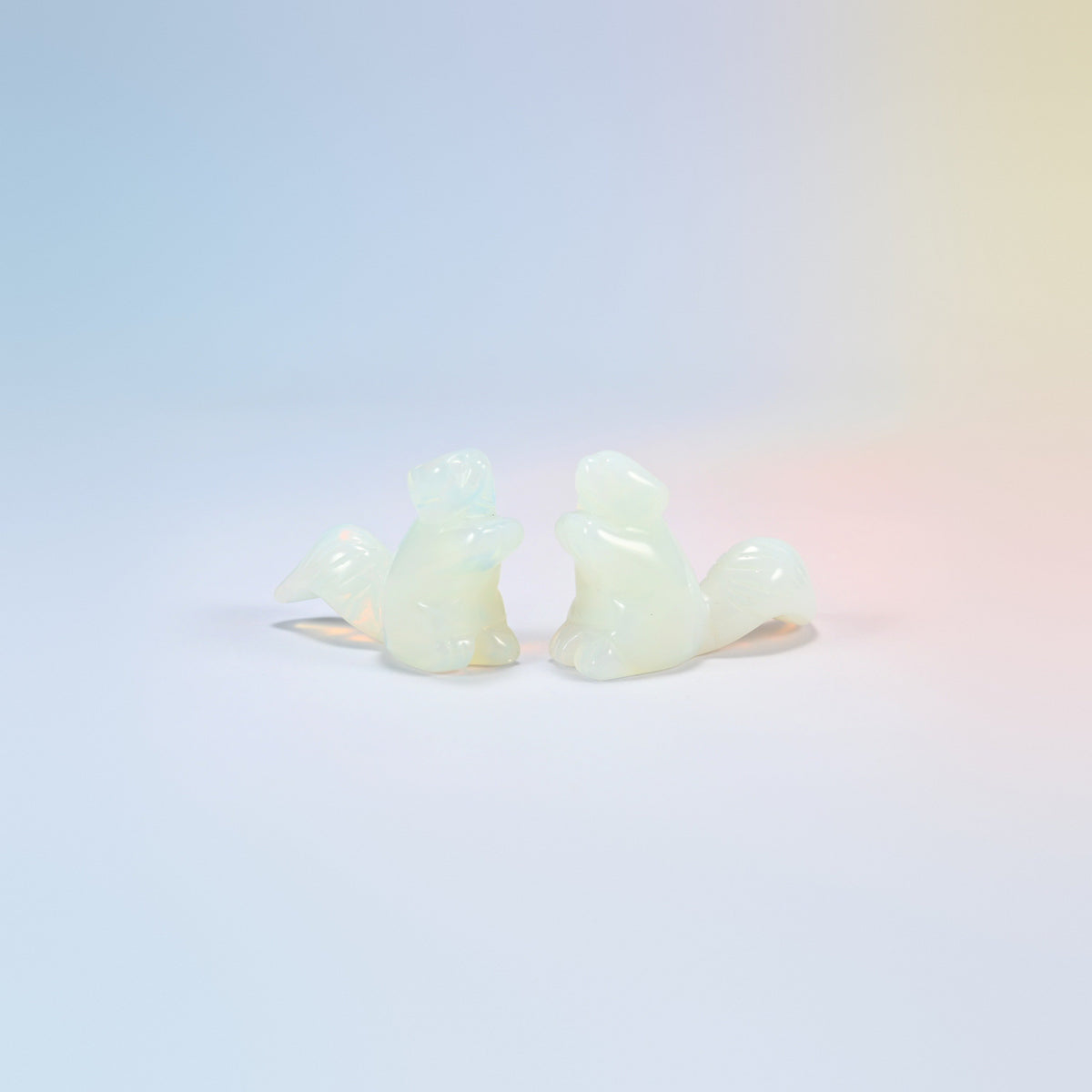 Two 2 inch opalite long tail squirrel carvings, milky man-made glass with a soft glow