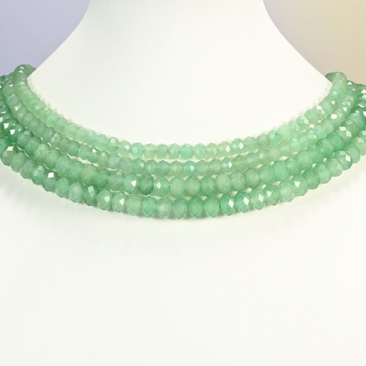 Green aventurine beads shown on a white neck display bust, the faceted rondelle strands sitting in even rows against the curve of the neck