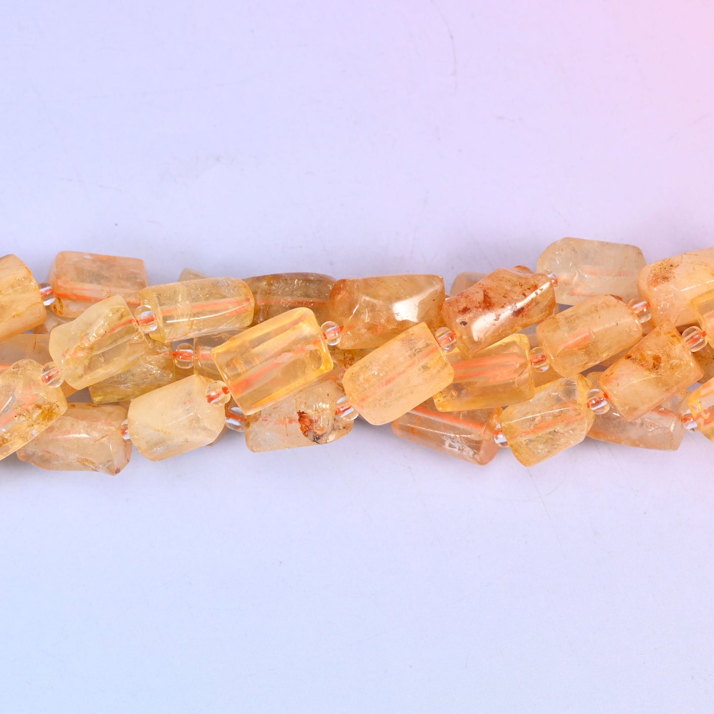 Faceted tubes with real heft to them, cut so the flat planes pass light around the stone rather than off a single curve — a substantial cylinder that still reads as refined on the wire.