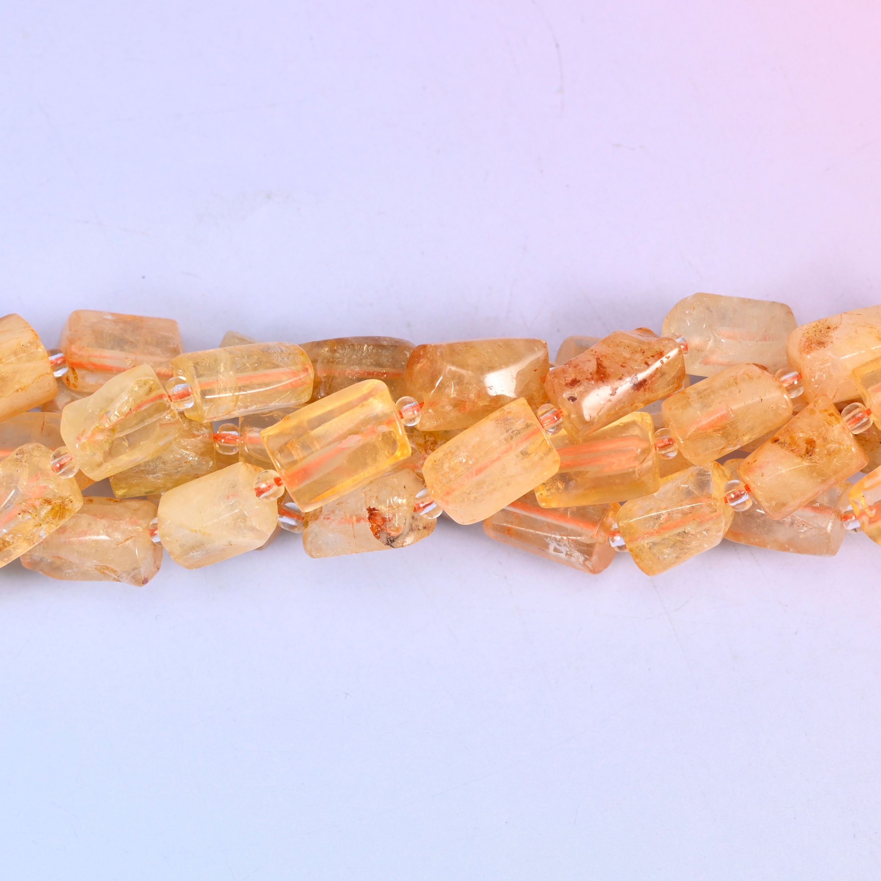 Faceted tubes with real heft to them, cut so the flat planes pass light around the stone rather than off a single curve — a substantial cylinder that still reads as refined on the wire.