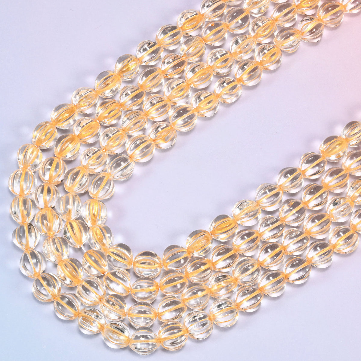 Clear gold pumpkin glass beads, several strands laid in a wide sweeping curve across the frame.