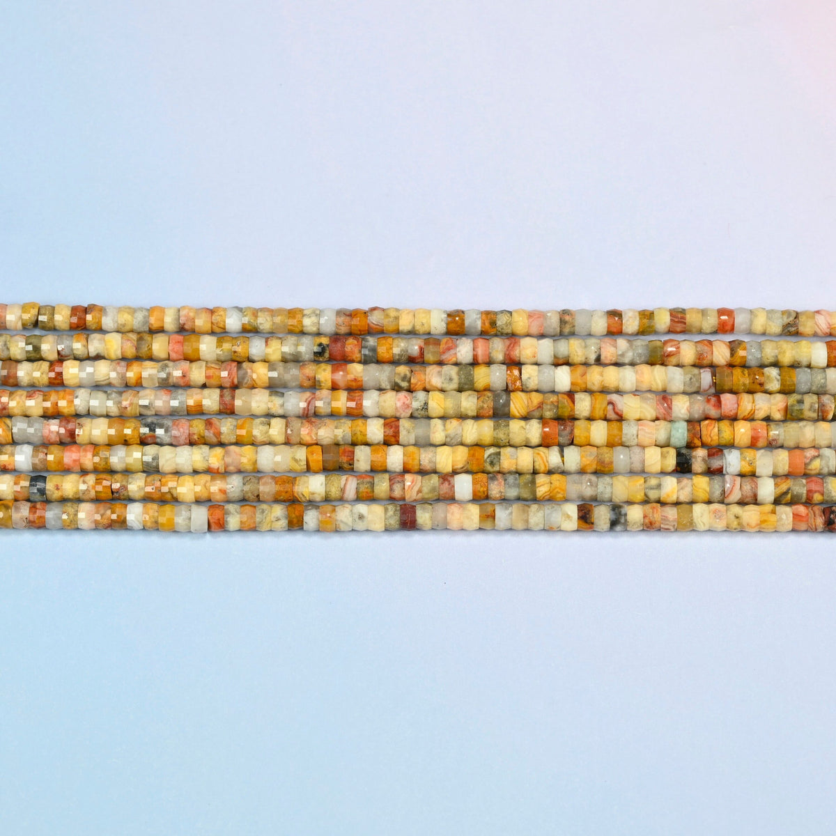 Several strands of crazy agate faceted heishi disc beads laid in straight rows