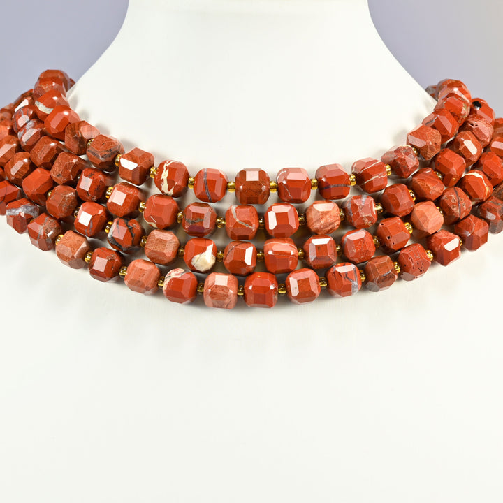 Flower red jasper faceted cube strands arranged as a layered collar on a white display bust, brick red beads with cream markings across the neck