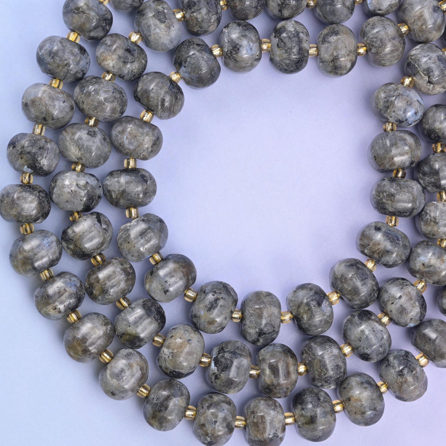 Overhead loop of pumpkin rondelle beads on a pale lavender surface